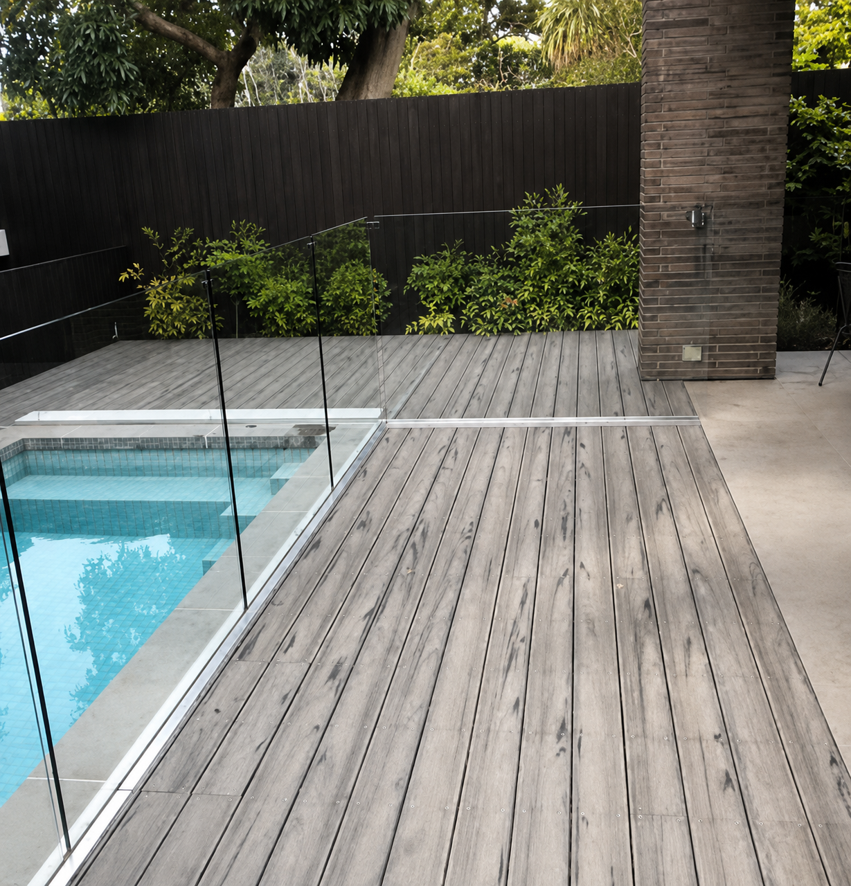 Grey composite decking around a pool with frameless glass balustrade, Williamstown